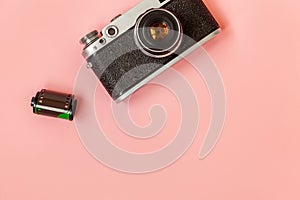 Vintage film photo camera lens and film roll on pink pastel trendy background