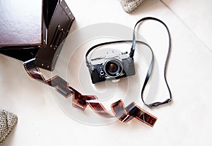 Vintage film rangefinder camera with leather case and photographic film on light colored background.