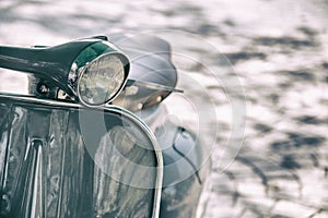 Vintage film style motorcycle headlight. Close up detail of elegantly designed vintage scooter parked in a street