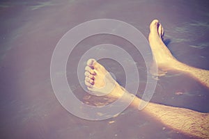 Vintage filtered male bare feet in lake water.