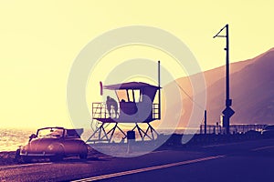 Vintage filtered sunset over beach with lifeguard tower.