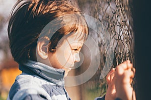 Vintage filthered photo of kid looking through the fence