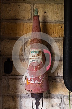 A vintage fire extinguisher, faded label and cone shaped