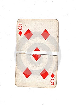 A vintage five of diamonds playing card torn in half.