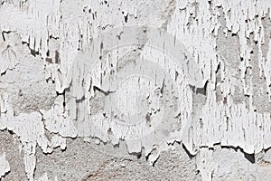 Vintage flakes of old white paint on grey concrete wall