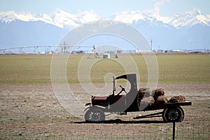 Vintage flatbed truck with hay bales in a farm field.