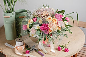 Vintage floristic background, colorful roses, antique scissors and a rope on an old wooden table