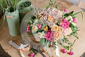 Vintage floristic background, colorful roses, antique scissors and a rope on an old wooden table