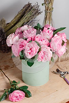 Vintage floristic background, colorful roses, antique scissors and a rope on an old wooden table