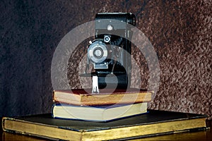 Vintage Folding Film Camera and Old Books on a Wooden Shelf