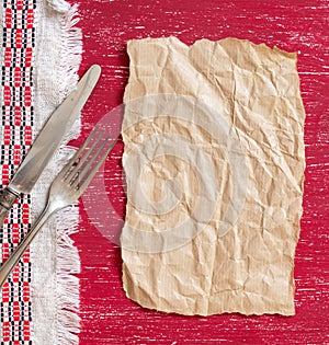 Vintage fork and knife on napkin on red wood and craft paper