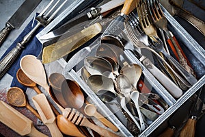 Vintage forks, spoons and knives in a dark old wooden box on a gray concrete or stone background. Selective focus.Top view. Copy