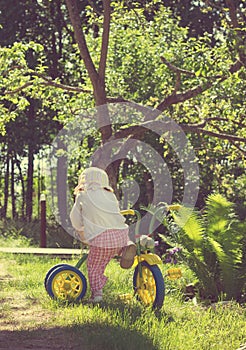 Vintage foto of Little child riding a bicycle on green grass