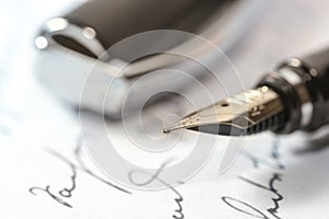 Vintage fountain pen with golden feather and cap on a handwritten paper, macro shot with selected focus