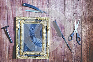 Vintage frame and hairdressing tools on wooden background