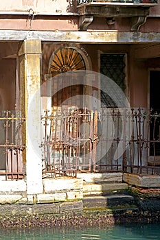 Vintage front door with wrought iron grille and wall with old weathered plaster in Venice, Italy