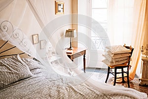 Vintage furniture retro sunny apartment with Baldachin bed, chair, cozy pillows, lamp, framed pictures on the walls photo