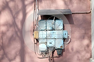 A vintage fuse box on a pink wall