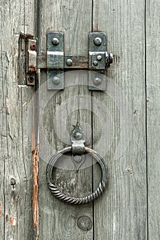 Vintage gate valves and old wooden gates with round metal handles in the form of rings.