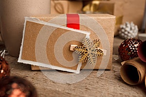 Vintage gift box package with blank gift tag on old wooden background, xmas decorative elements. Christmas festive close up