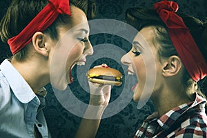 Vintage girlfriends in old style dress eat hamburgers photo