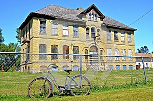 Vintage girls bike leans against a fence of a former old high school building