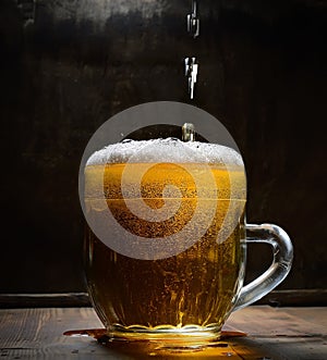 Vintage glass of beer with foam on a wooden board against a dark background