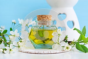 Vintage glass bottle with cosmetic oil massage oil, tincture, infusion, extract and white flowers close up. Aromatherapy, spa