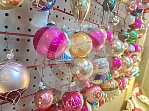 Vintage Glass Christmas Ornaments in an Antique Mall, hanging from a Pegboard. Silver, gold, pink spheres for decorating the tree.