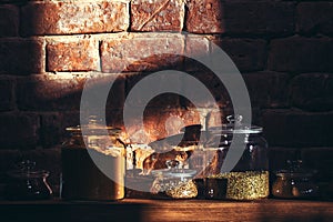 Vintage glass jars of assorted spices on a wooden shelf