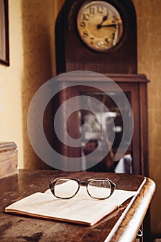 Vintage glasses on old book, old clock in background