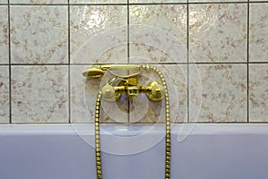 Vintage gold bathtub faucet and ceramic tiles in background.Retro bronze look. antique design