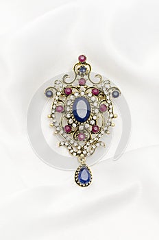 Vintage gold brooch with precious stones on white silk