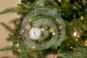 Vintage gold old retro clocks hang on branch of green Christmas tree background. Photo for greeting cards. Xmas mood. Decorated