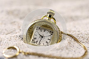 A vintage gold old watch in the sand .