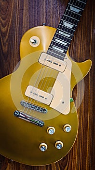 Vintage gold top single cutaway guitar on wood surface