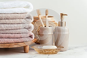 Vintage golden bath supplies with stack of clean soft towels next to soap and toothbrushes. White, pink and beige towels with
