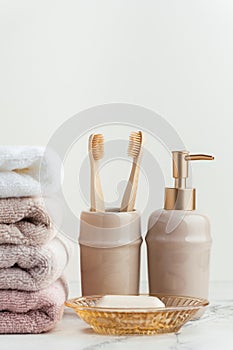 Vintage golden bath supplies with stack of clean soft towels next to soap and toothbrushes. White, pink and beige towels with