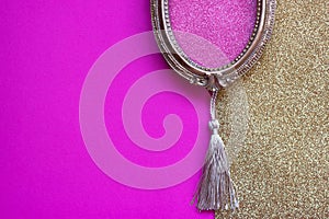 Vintage golden oval picture frame on pink and golden background, with copy space in the frame