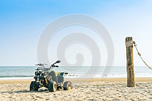 Vintage green ATV on the sandy beach. Quad ATV all terrain vehicle parked on beach, Motor bikes ready for action with summer sun