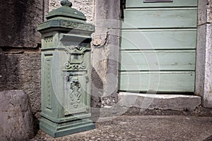 Vintage green mailbox near rustic door in Europe.