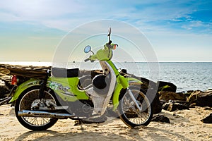 A vintage green motorbike park on the beach, sea background