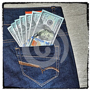 Vintage grunge American money is in the pocket of blue jeans.