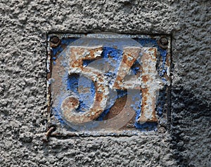 Vintage grunge square metal rusty plate of number of street address with number.