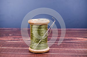 Vintage grunge wooden green thread spool with needle