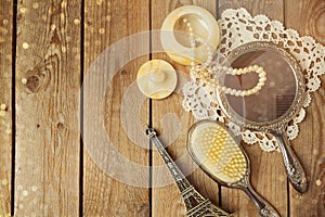 Vintage hand mirror and hairbrush with Eiffel Tower on wooden background.