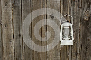 White vintage handle gas lantern on rustic wooden wall.