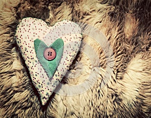 Vintage handmade plush heart pillow on soft blanket