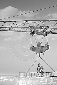 Vintage handyman having lunch on a crossbar hanging above the ci