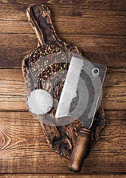Vintage hatchet for meat on wooden chopping board with salt and pepper on wooden table background